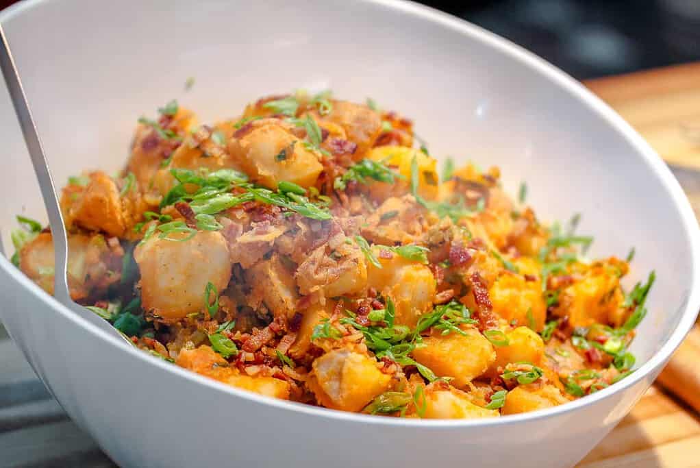 Spicy potatoes with scallion and bacon in a white bowl