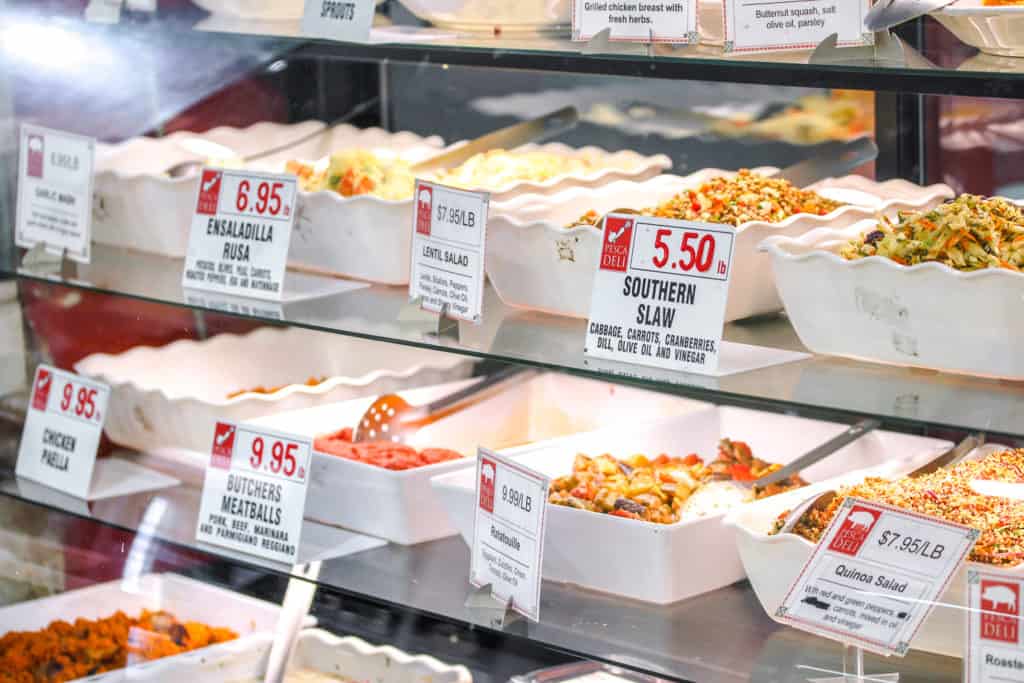 prepared salads in bowls behind a glass case