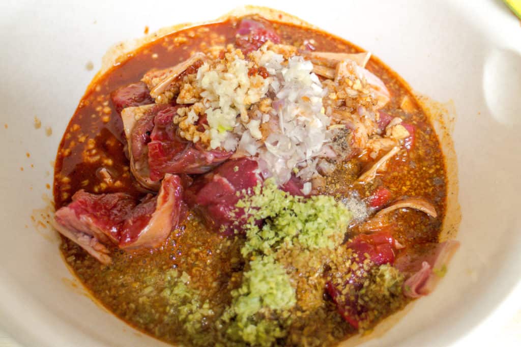 white bowl with chunks of beef, marinade mix, lemongrass, garlic and shallot