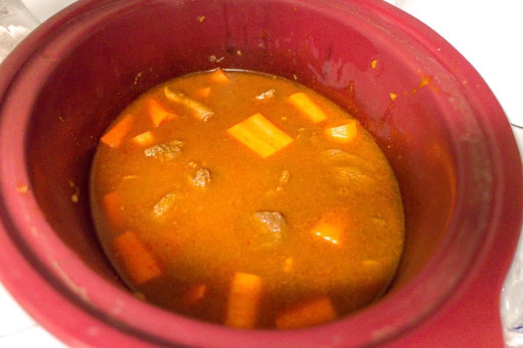 red crock pot with bo kho (vietnamese beef stew) in it. 