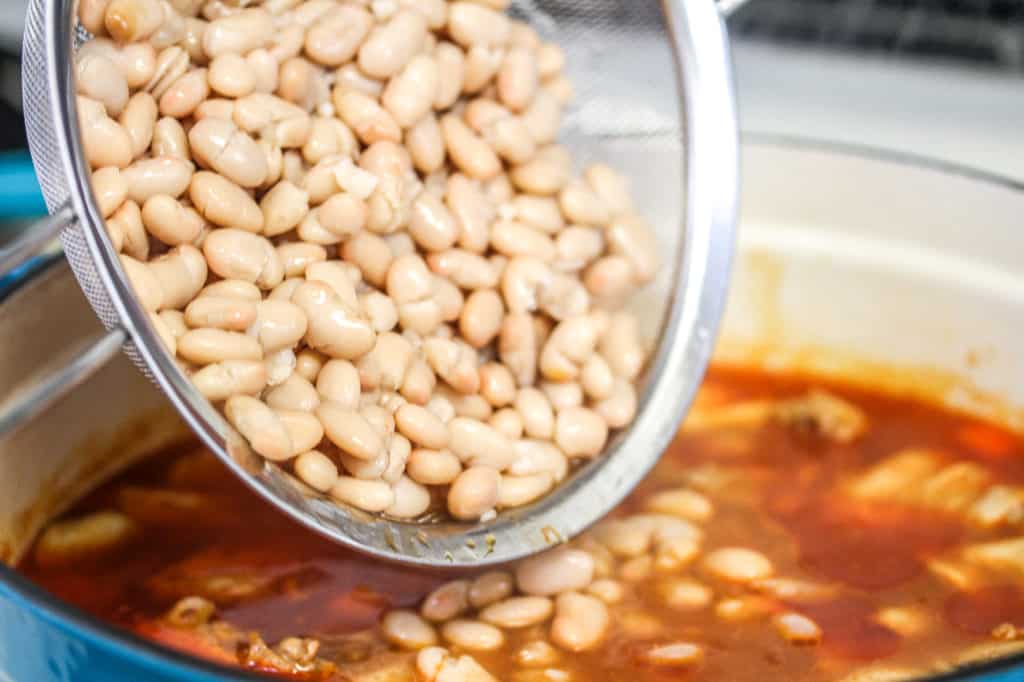 adding beans to marinated chicken for gà nấu đậu