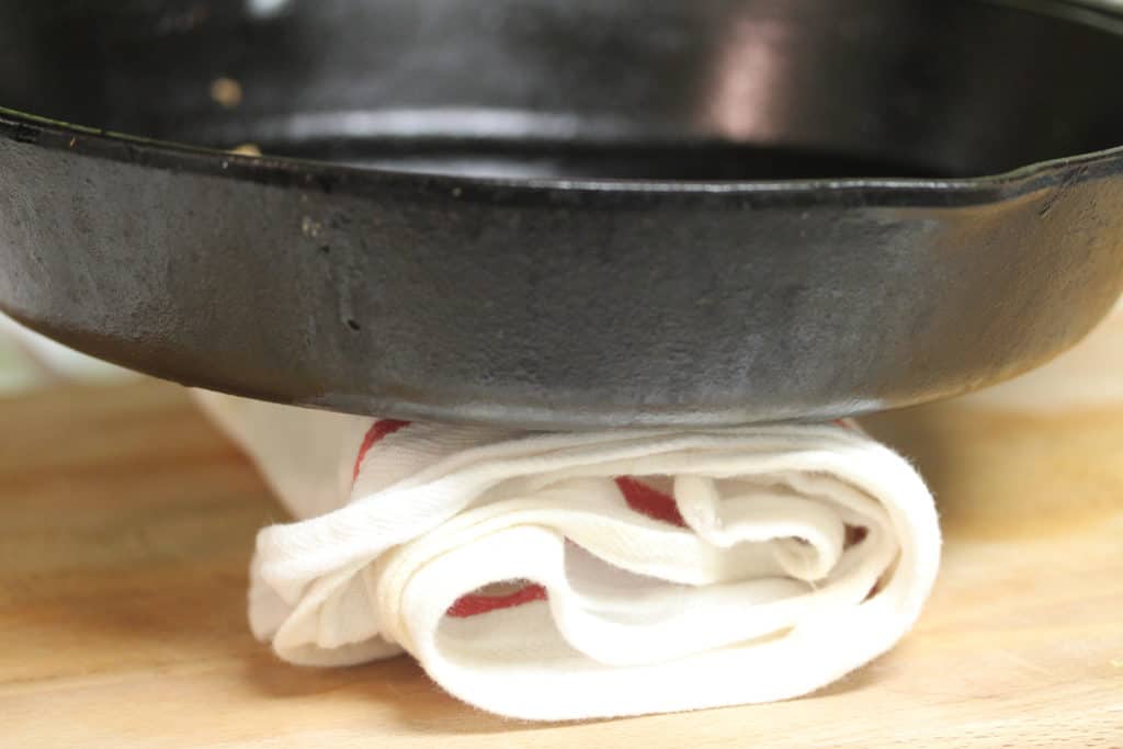 Black cast iron skillet sitting on top of a bundle wrapped in a white dish towel