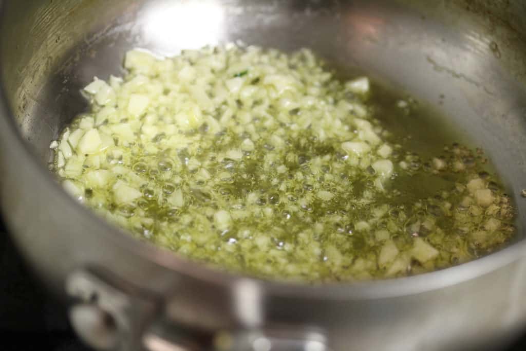 garlic sizzling in oil in a stainless steel saucepot