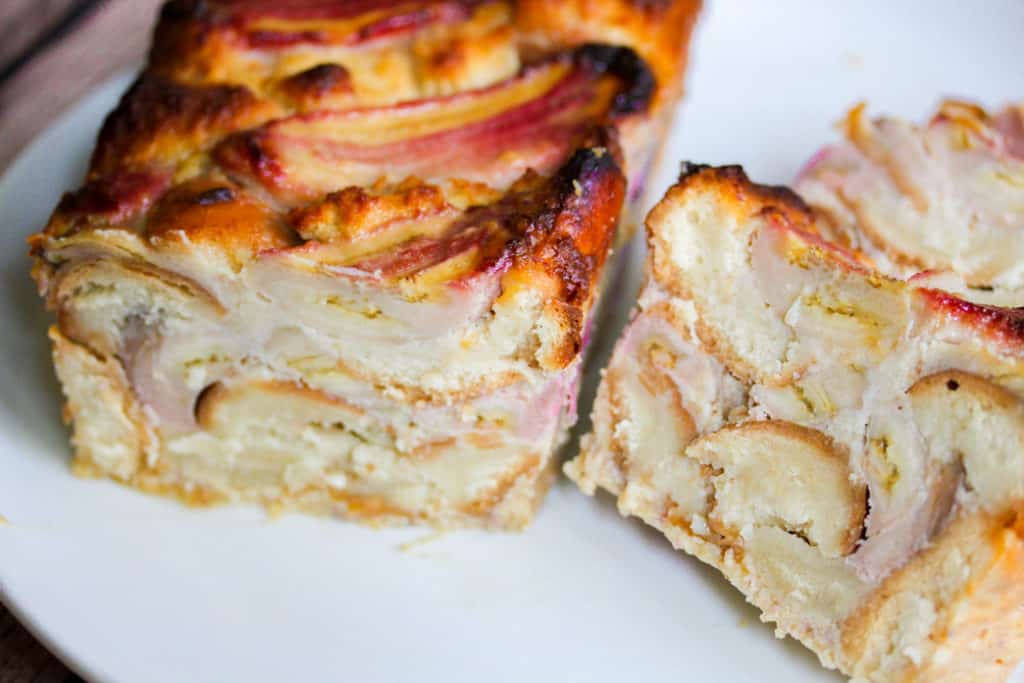 A close up shot of half a loaf of banana bread pudding with a slice of the banana bread placed to the right of it.