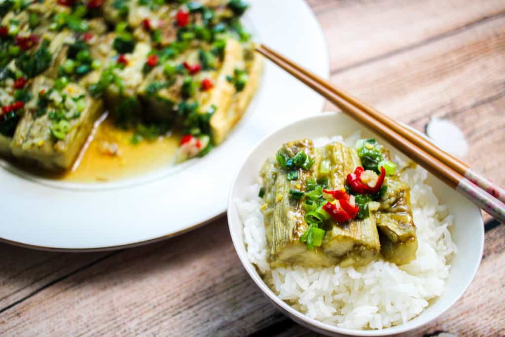 small bowl with grilled eggplant, scallions and chilis in front of a plate of eggplant