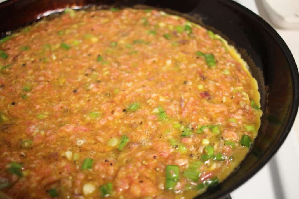 raw Chả Trứng Chiên mixture cooking in a pan