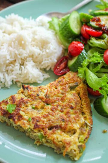 A slice of Chả Trứng Chiên served with white rice and a side salad.