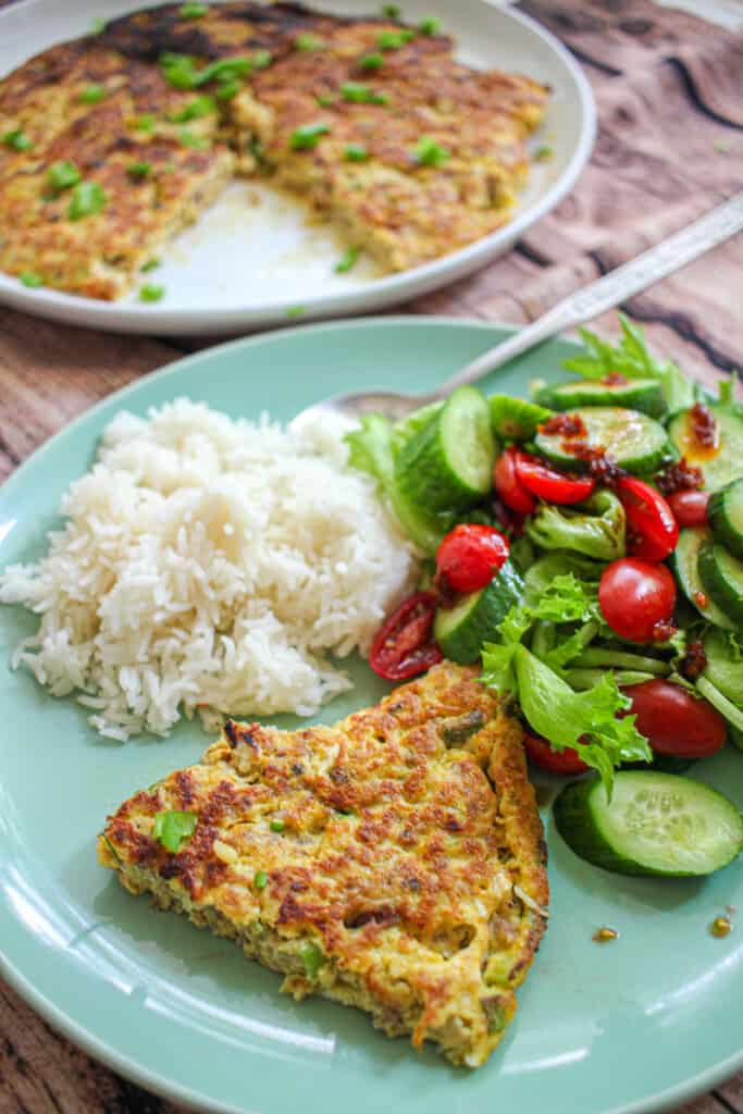 A slice of Chả Trứng Chiên served with white rice and a side salad.