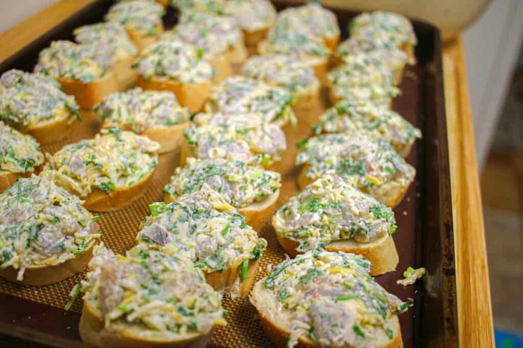 slices of baguette topped with mixed shrimp mixture on a cookie sheet