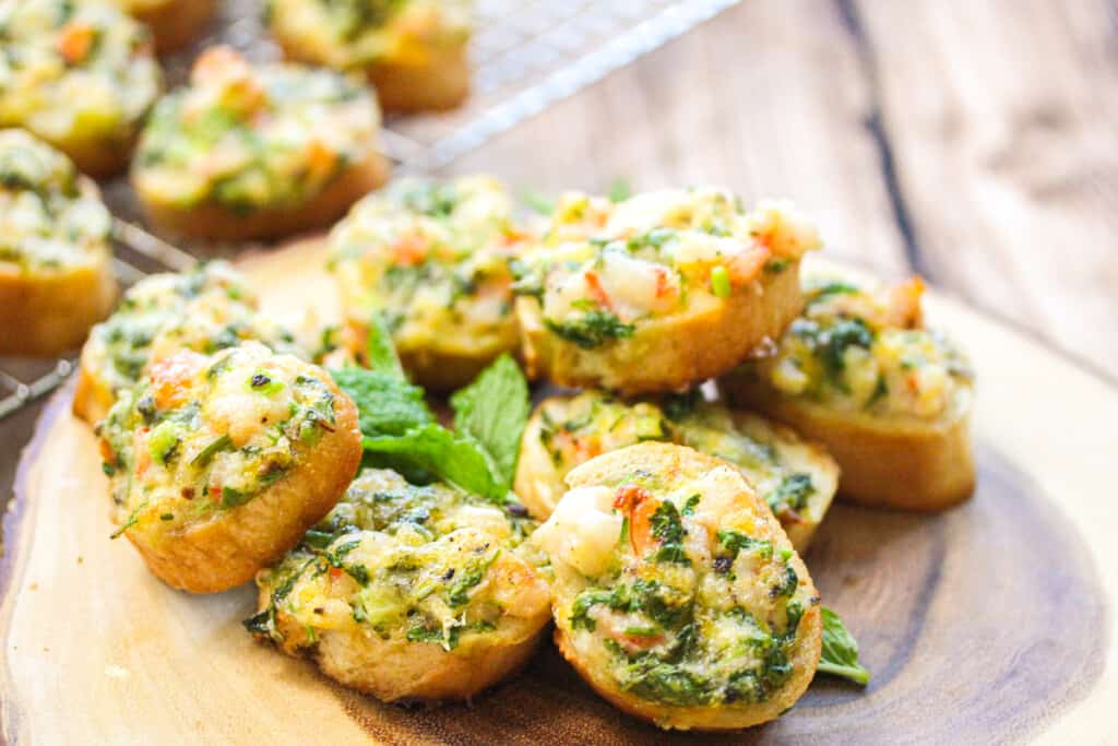 Cooked shrimp toasts piled on a wooden plank