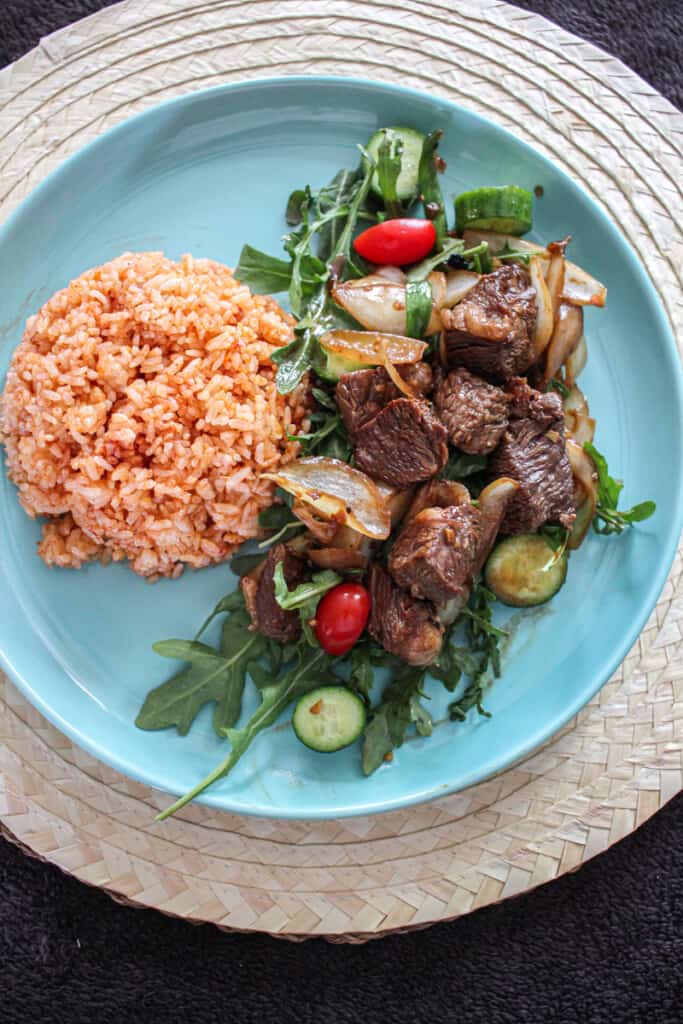 a serving of Bò Lúc Lắc and vegetables with red rice