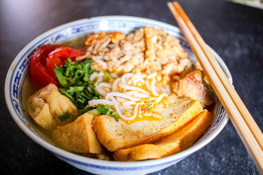 A set of chopsticks rests on a bowl of bun rieu