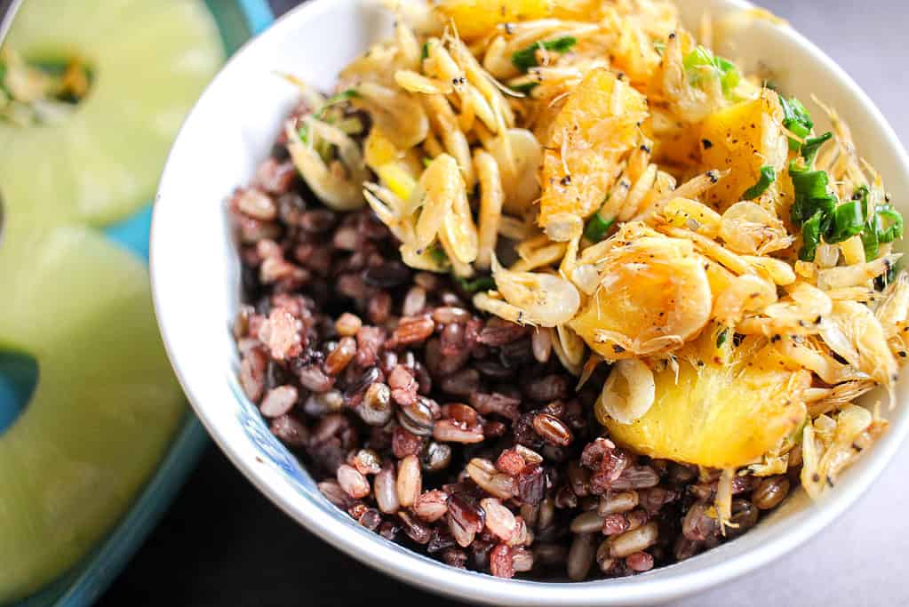 A close up of A small bowl of multigrain rice and dried shrimp and pineapple stir fry