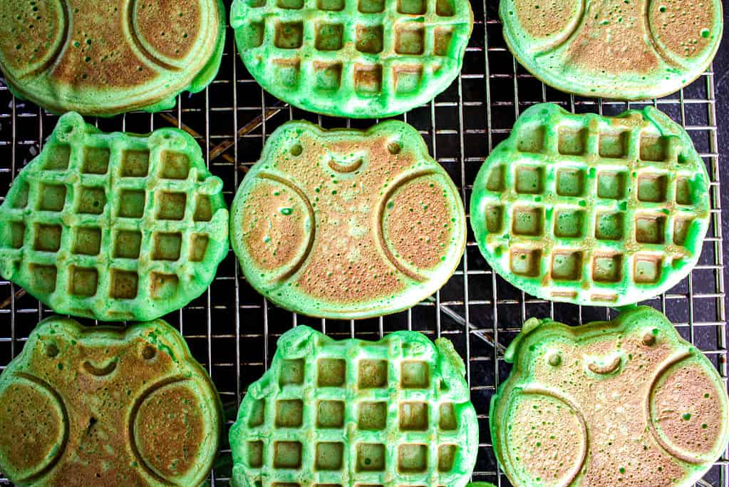 frog shaped coconut pandan waffles (Bánh Kẹp Lá Dứa) arranged on a wire rack to show the front and back of the waffles.