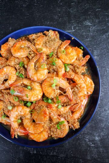 Vietnamese braised shrimp, or Tôm Kho Tàu, on a blue plate on top of a black slate background