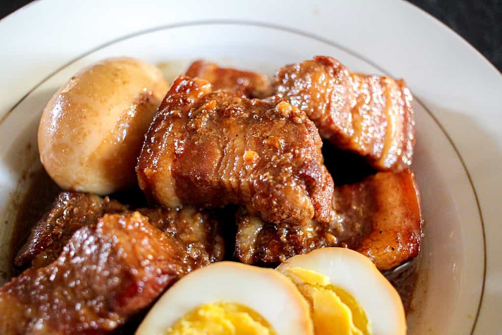 A close up image of a piece of Caramelized Pork Belly and Eggs (Thịt Kho Trứng) in a white bowl