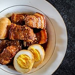 A white and gold bowl filled with Caramelized Pork Belly and Eggs (Thịt Kho Trứng)