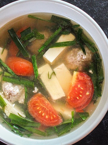 A square crop of a bowl of Vietnamese Tofu Soup with Tomato and Chives (Canh hẹ Đậu Hũ Cà Chua)