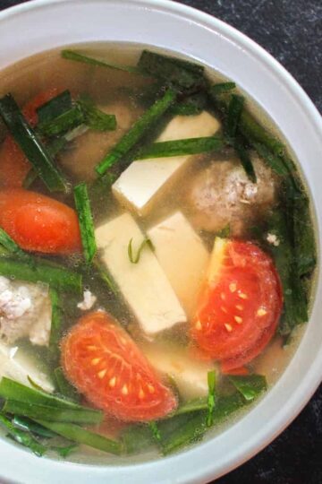 A square crop of a bowl of Vietnamese Tofu Soup with Tomato and Chives (Canh hẹ Đậu Hũ Cà Chua)