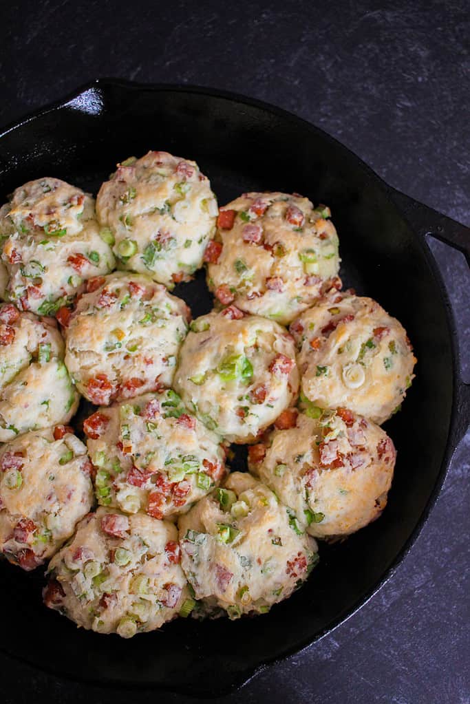 a bird's eye view of cooked spam and scallion biscuits in a cast iron skillet