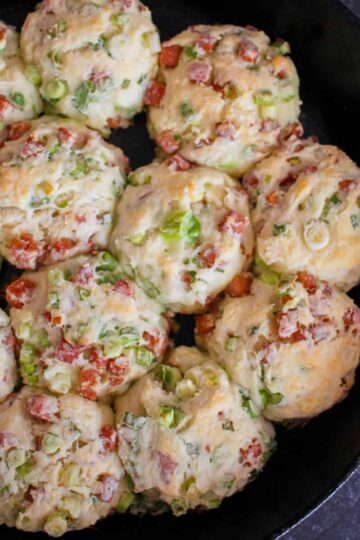a bird's eye view of cooked spam and scallion biscuits in a cast iron skillet