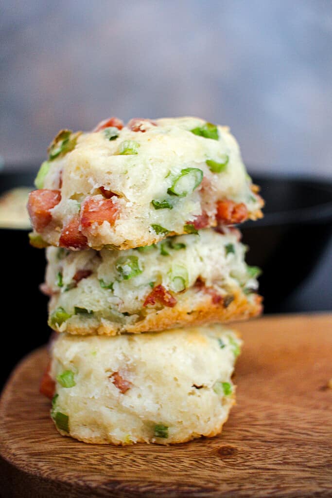 Three cooked spam and scallion biscuits stacked on top of each other on a wooden cutting board