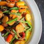 A plate of Vietnamese potato salad, which consists of potatoes, green beans, shallots, carrots and vinaigrette, on a plate on a table.