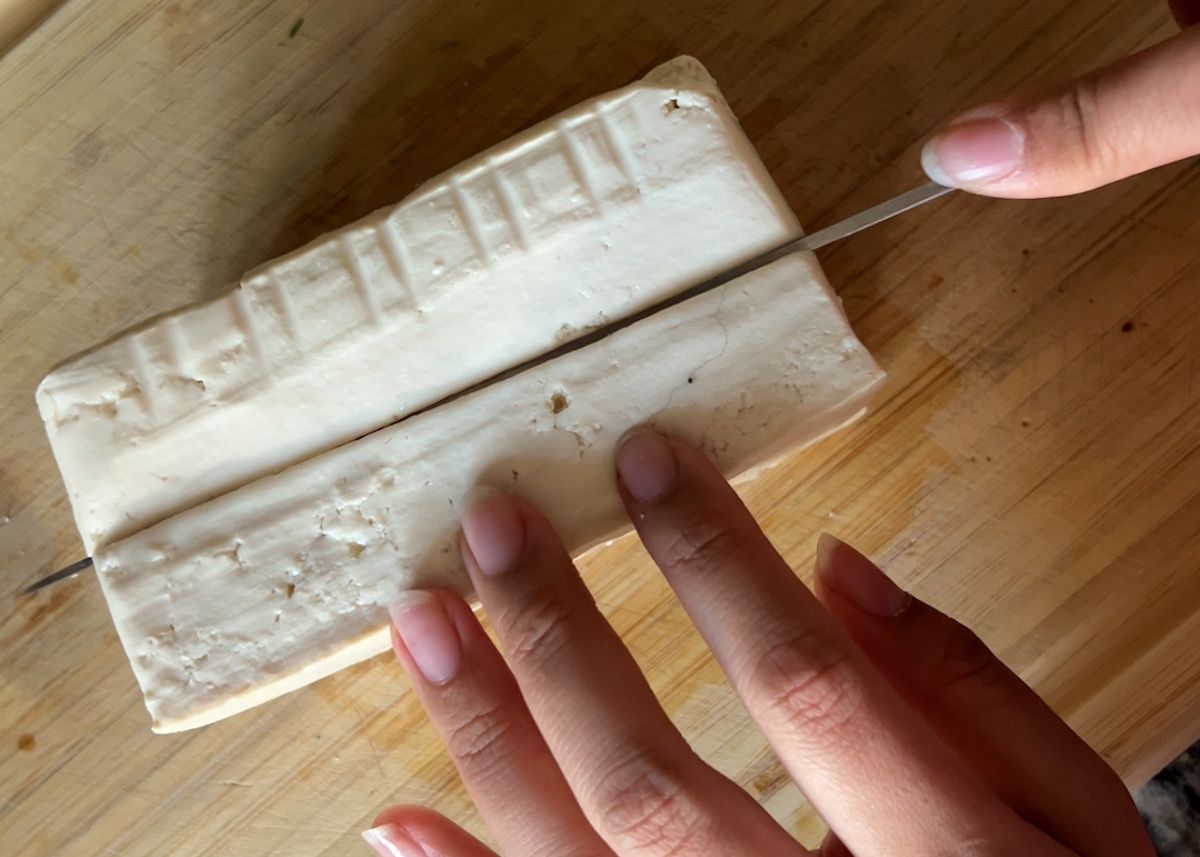 hands slicing a block of tofu