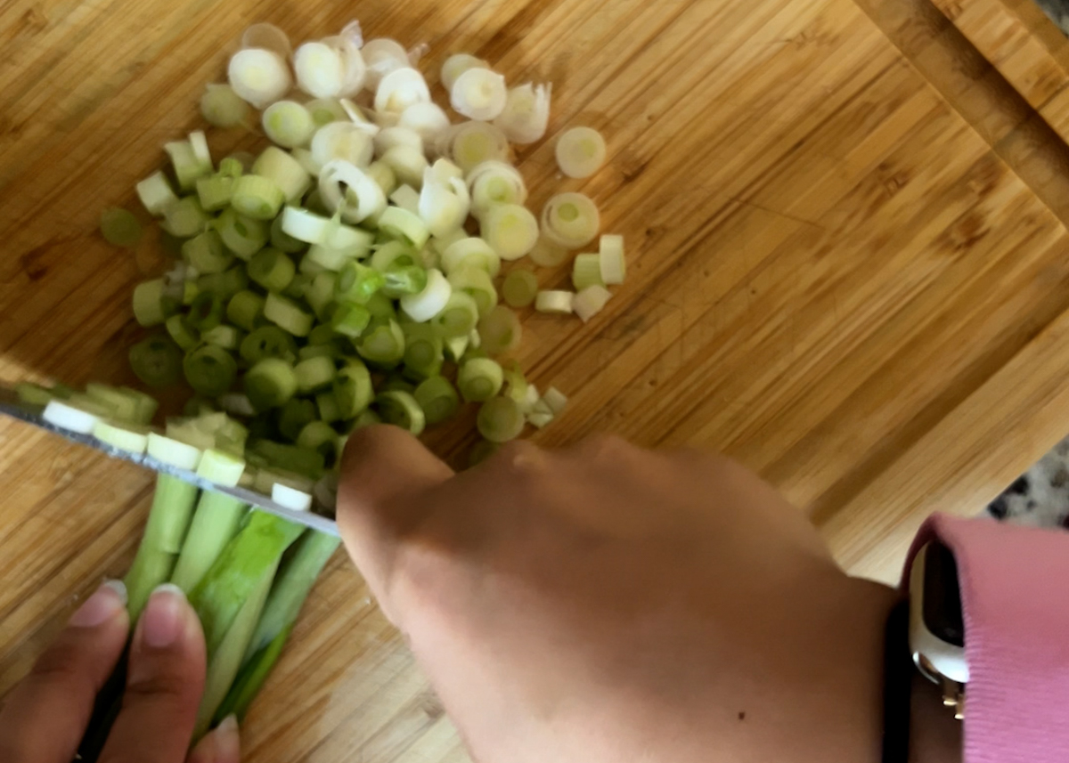 hands chopping a bunch of scallions