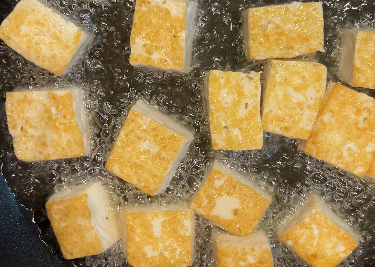 golden brown chunks of tofu sizzling in oil